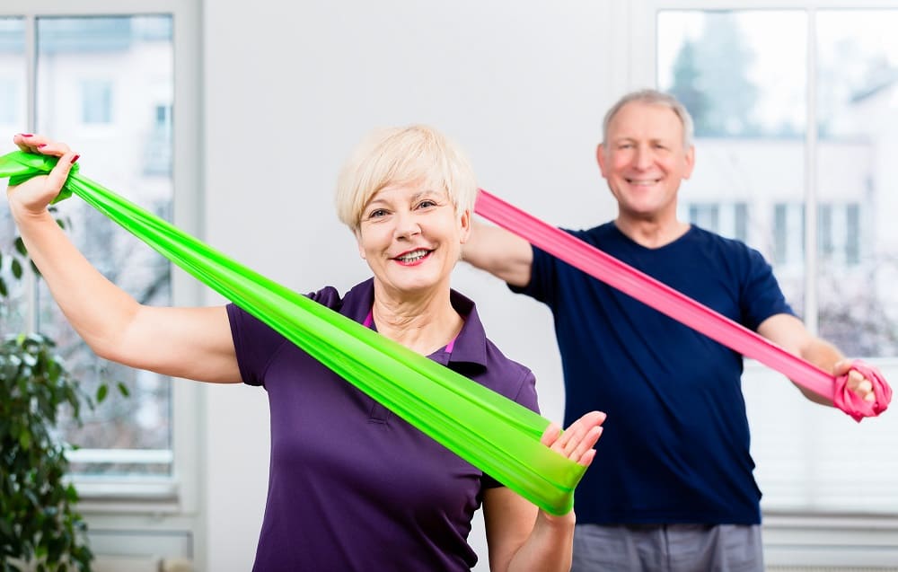ældre mennesker træner med elastik